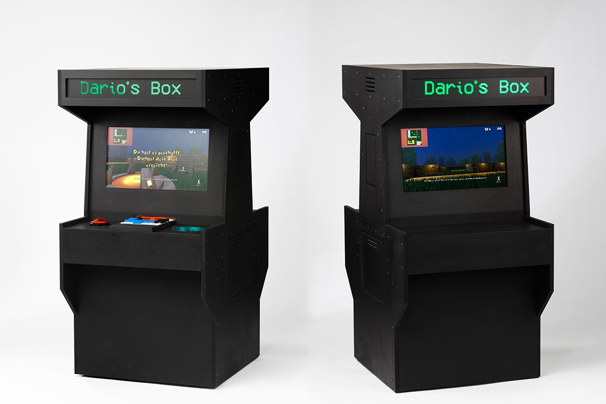 Two black arcade-style cabinets stand side-by-side on a white background. Each cabinet has a screen displaying a video game, with the words 'Dario's Box' in green lights above the screen.
