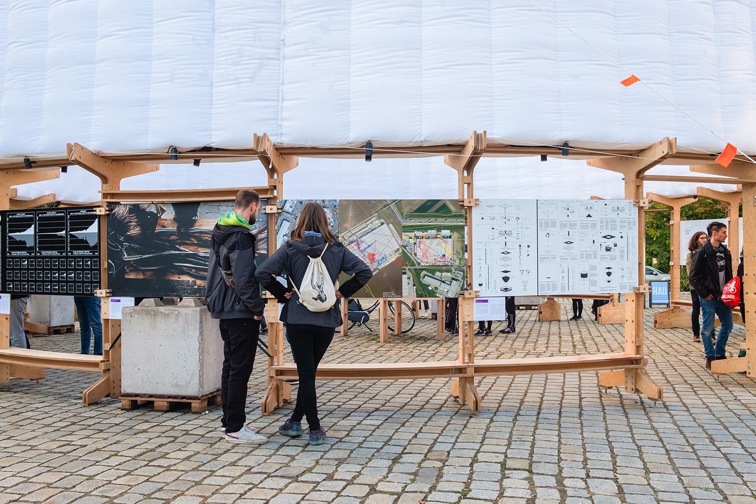 Two people standing in front of a setup that displays a printed version of 3 of the locations that have been passed by the GPS trackers.